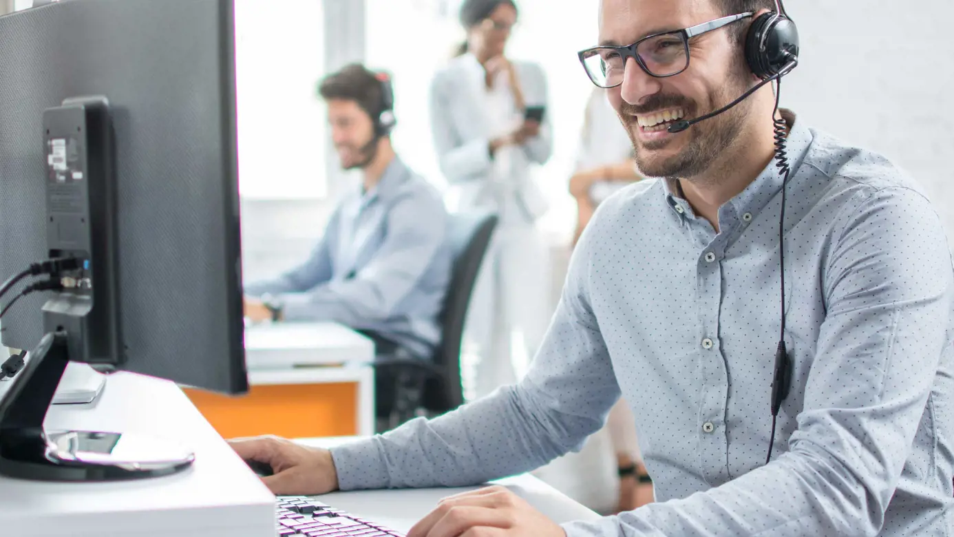Man laughing while talking into headset